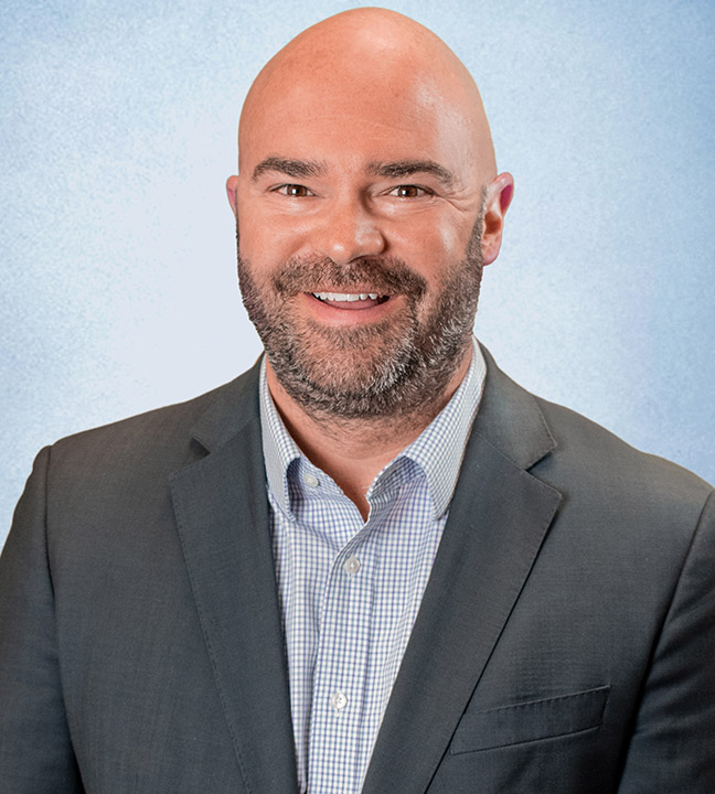 Chris Anderson headshot - smiling bald man with beard wearing gray suit