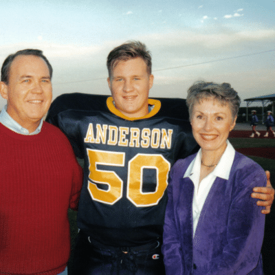 Drew in football uniform with mom and dad